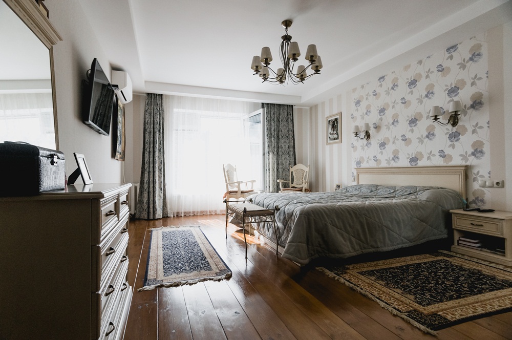spavaća soba i krevet u središtu uz tapacirani namještaj, tradicionalne tepihe, zavjese i tapete