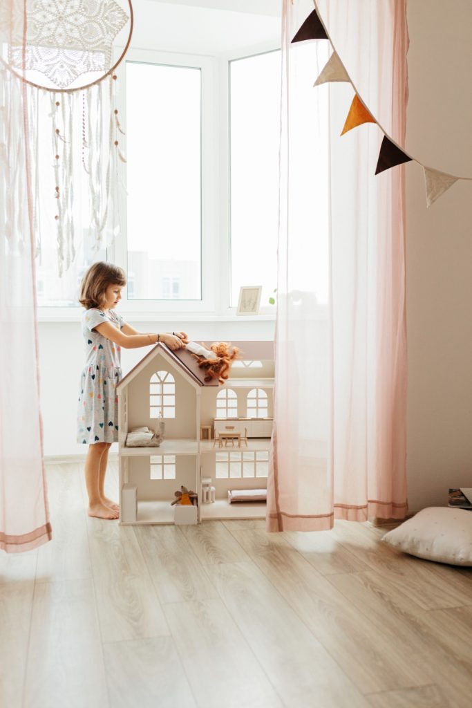 Djevojčica se igra sa kućicom za lutke u svojoj sobi